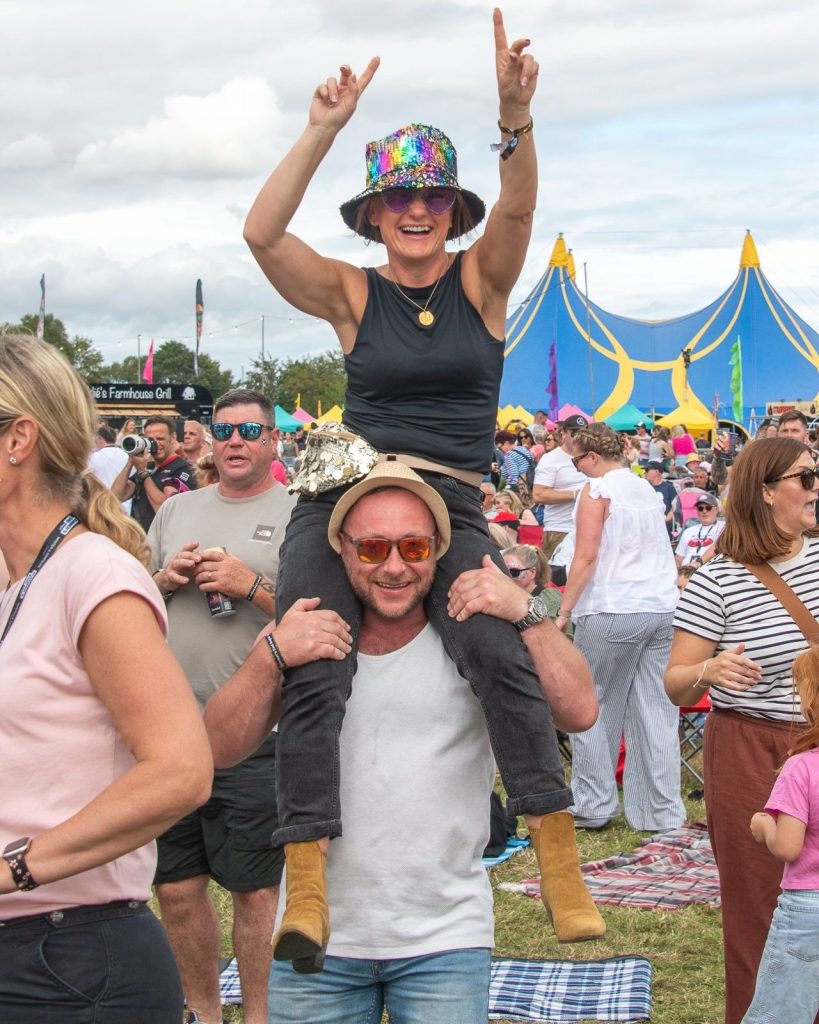 A festival goer on shoulders in front of the big top