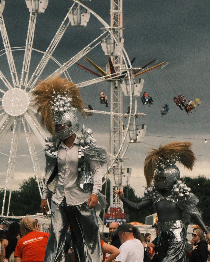 Two silver stilt performers by the big wheel